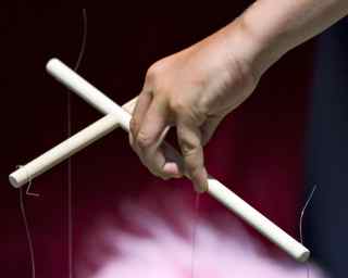 Cross holding puppet strings